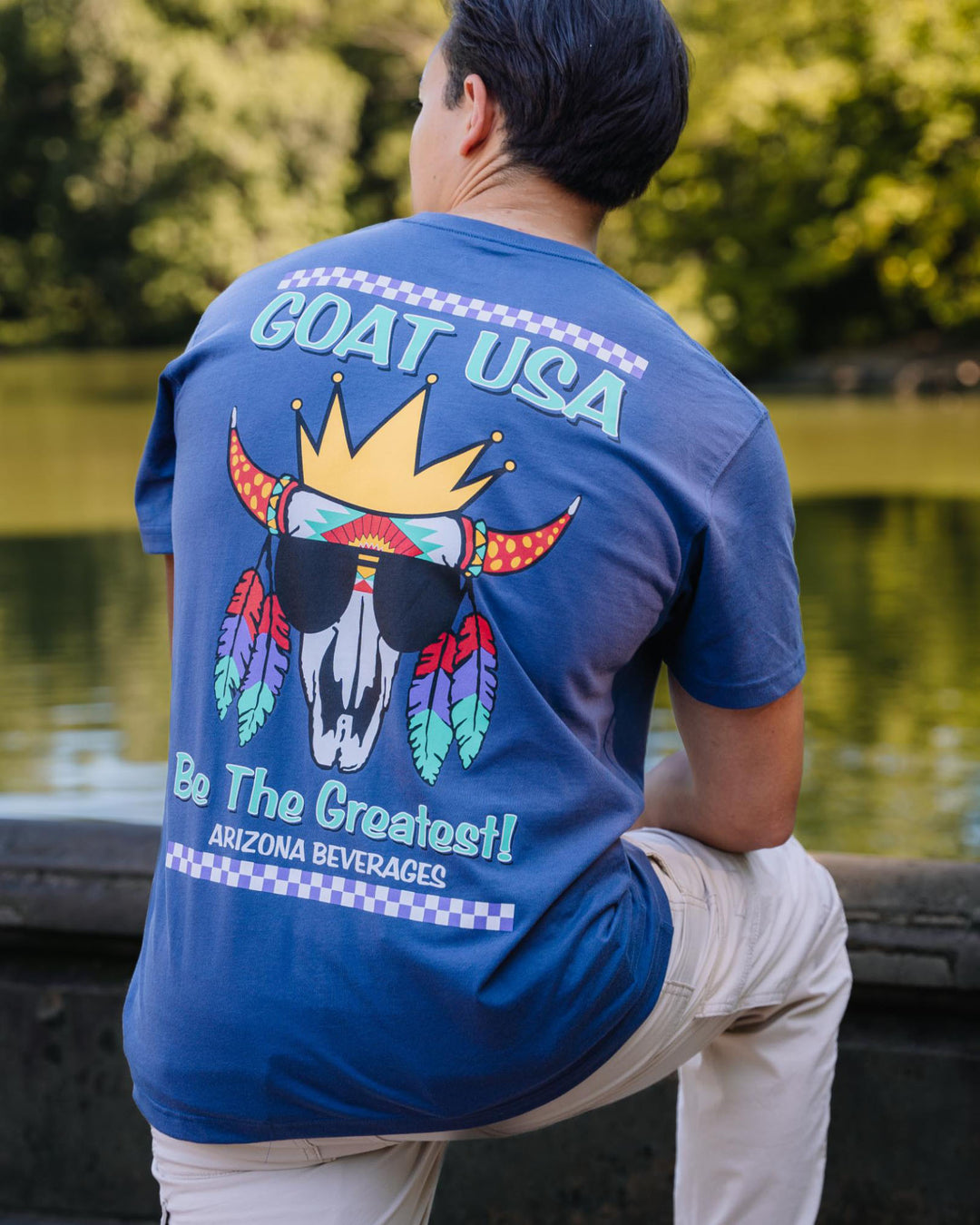 Guy in front of a pond wearing the AriZona x GOAT USA skull goat t-shirt