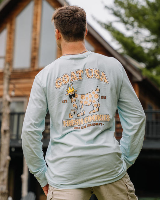 Guy facing house wearing ice blue cookie goat long sleeve