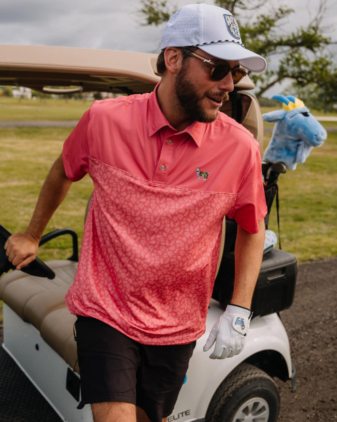 Man stepping out of golf cart wearing salmon polo