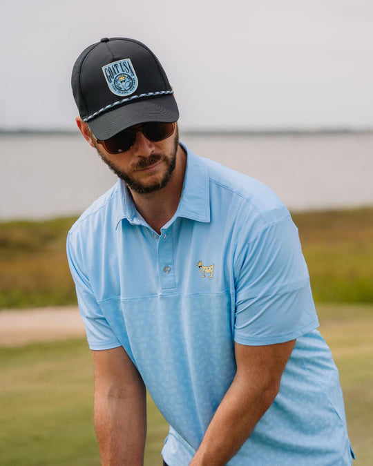 Man eyeing down a putt in a blue polo