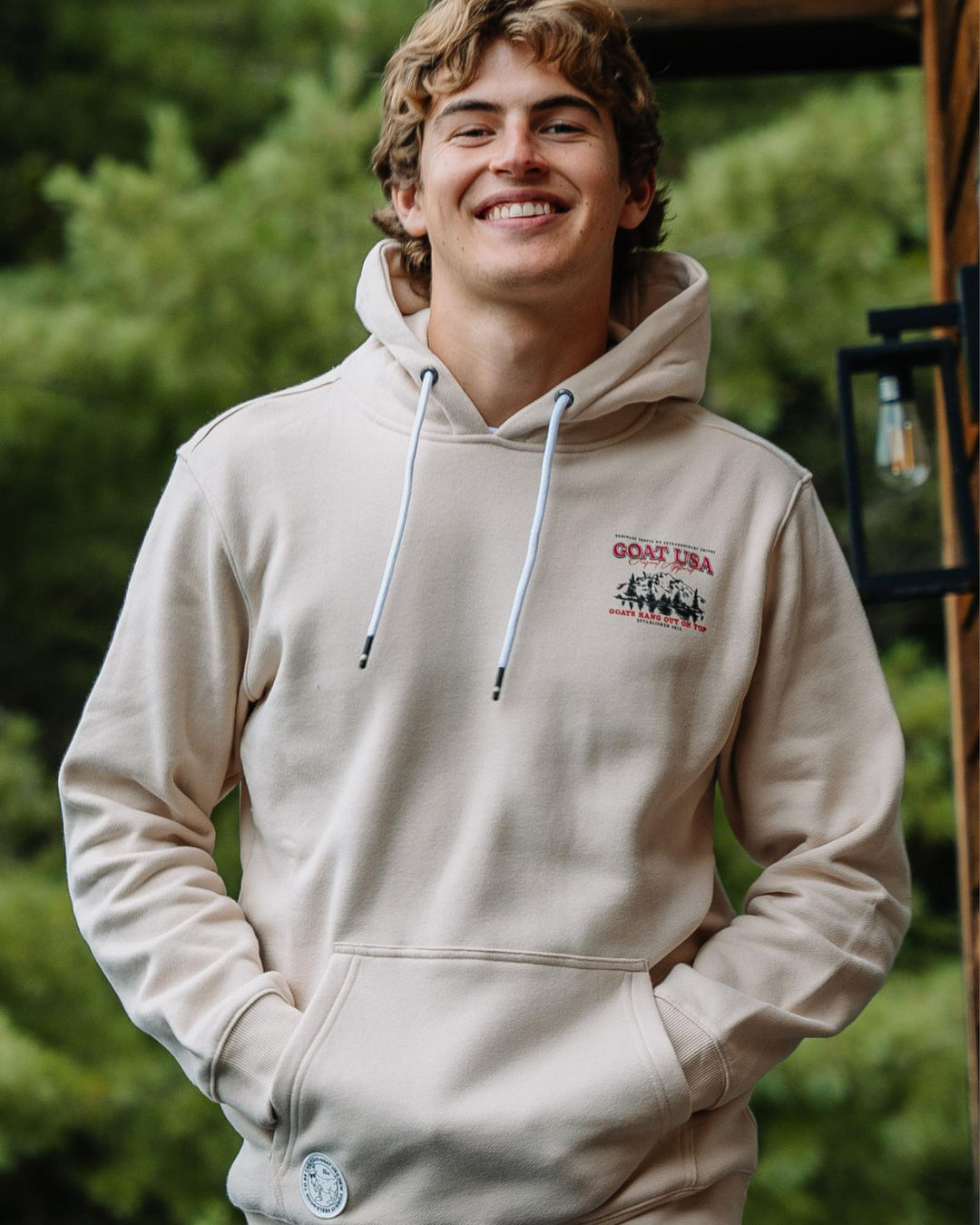 Male model smiling with hands in sweatshirt pocket 