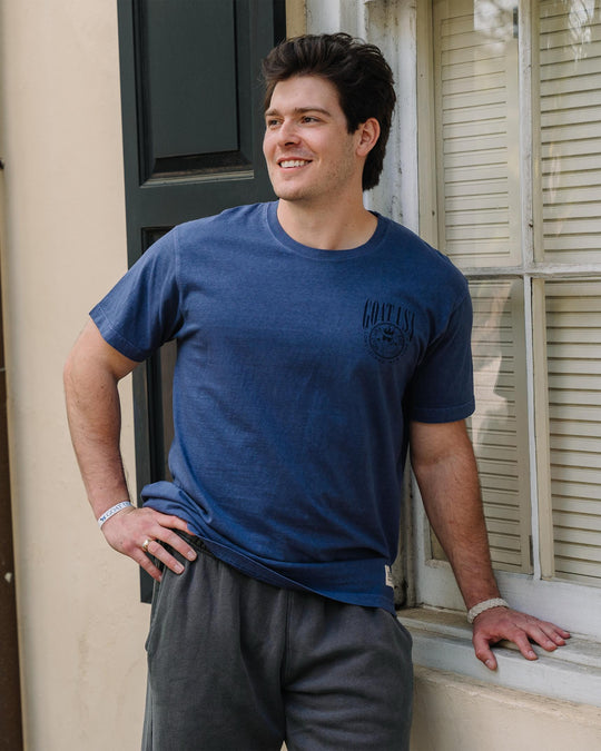 Man smiling while leaning up against window sill #color_navy