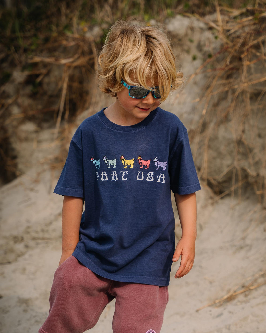 Kid on beach looking at the sand