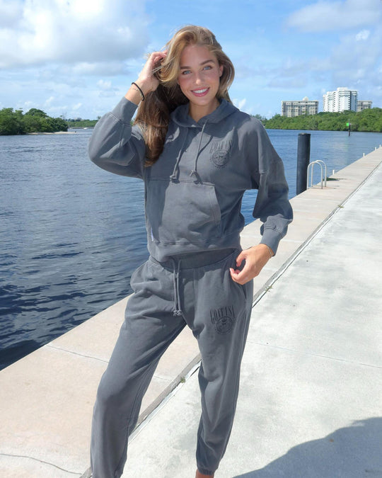 Girl posing in pepper-colored Origin Hoodie standing on seawall#color_pepper